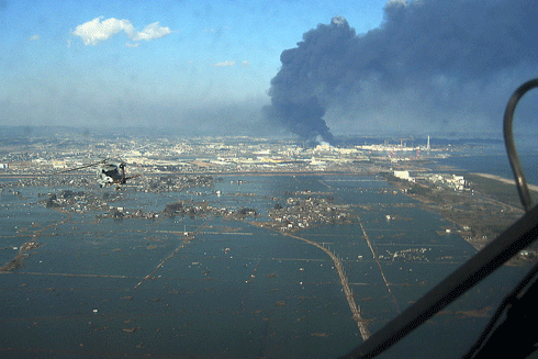 A naval helicopter flies over the port of Sendai to deliver food to survivors of Japan’s devastating 9.0 magnitude earthquake and tsunami in 2011 – an oil refinery is burning in the background. CSIRO researchers have developed algorithms that can be applied to data collected by various federal and state government agencies to aid in the planning and prediction of natural hazard impacts.